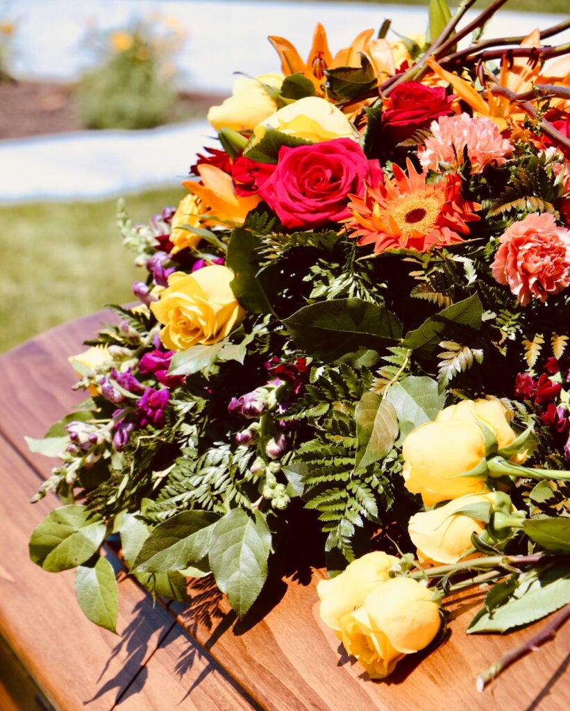 Lovely floral arrangement on wood casket.